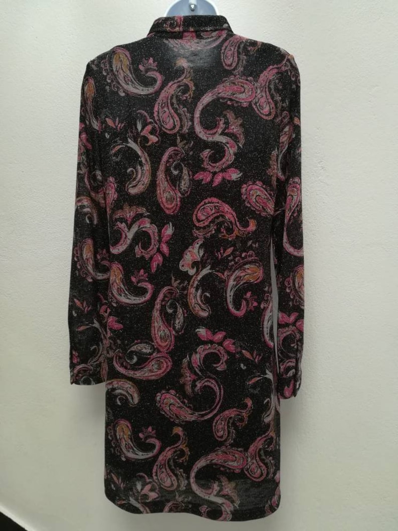 May include: A long-sleeved black shirt with a paisley pattern in shades of pink, orange, and white. The shirt has a collared neckline and a button-up front.