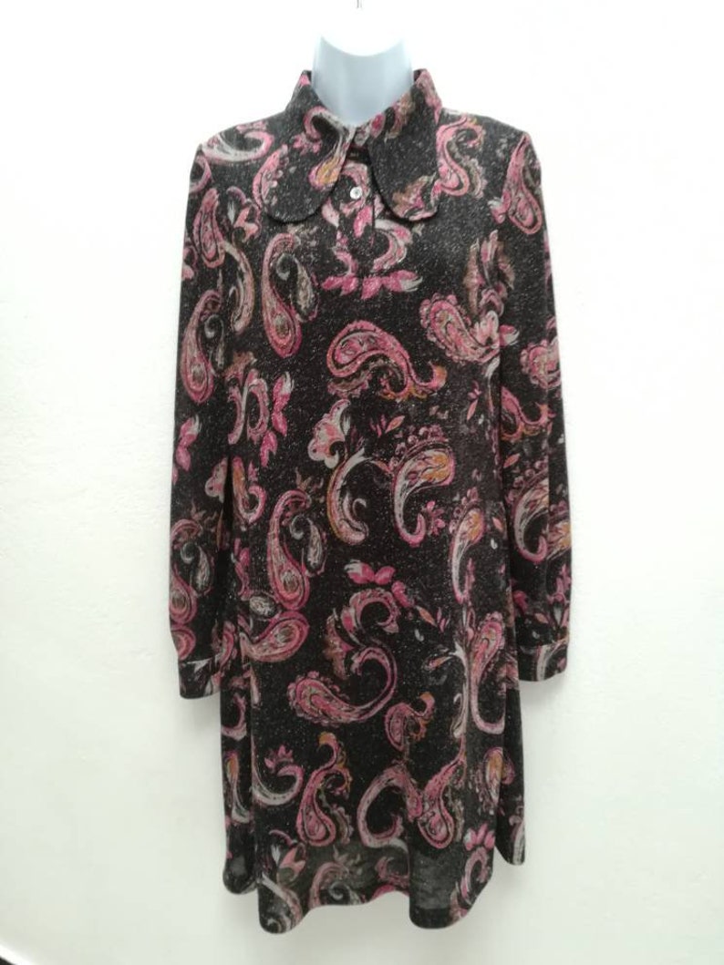 May include: A long-sleeved dress with a paisley print in shades of pink, brown, and white. The dress has a collared neckline and a button closure.