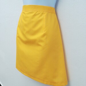 May include: A yellow skirt with white polka dots. The skirt is A-line and has a simple design.
