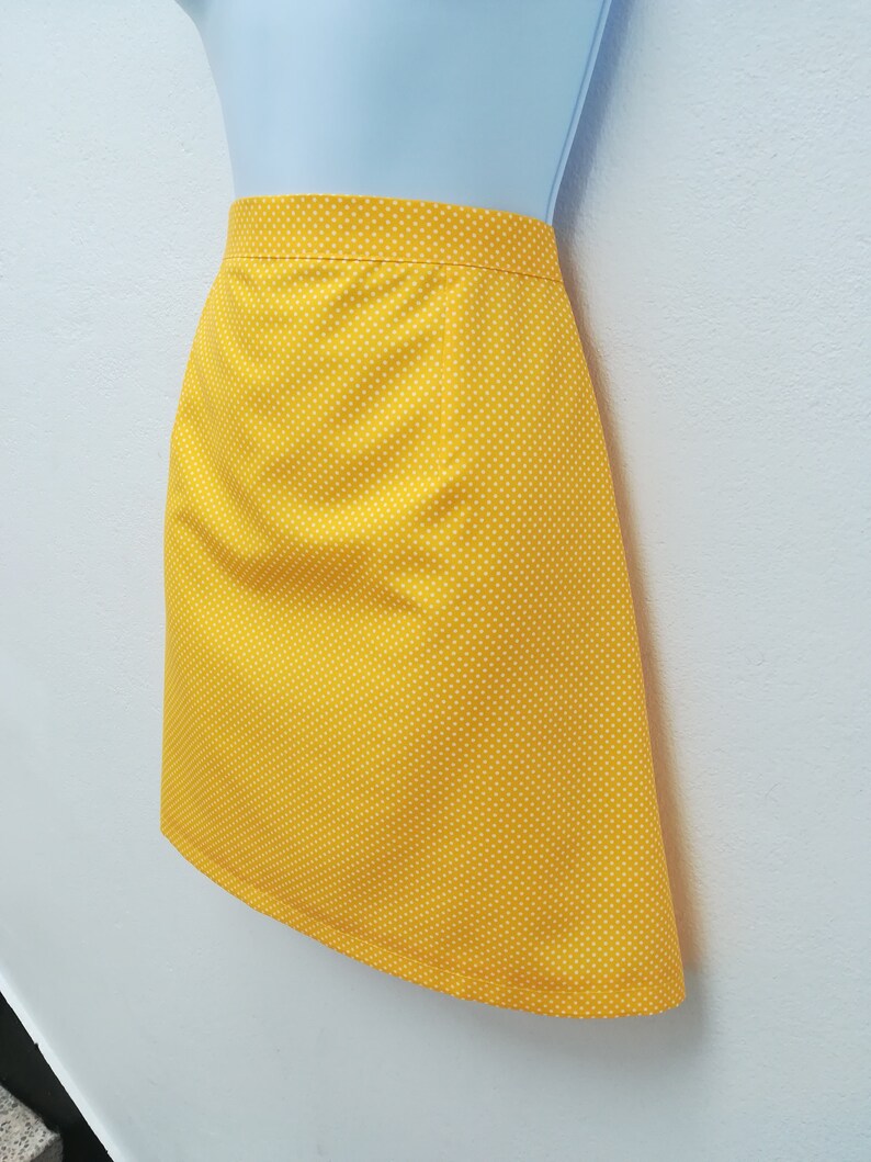 May include: A yellow skirt with white polka dots. The skirt is A-line and has a simple design.