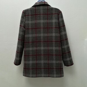 Puede incluir: Una chaqueta de traje gris y burdeos a cuadros con cuello de muesca y mangas largas.