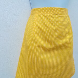May include: A yellow skirt with white polka dots. The skirt is knee-length and has a straight silhouette.