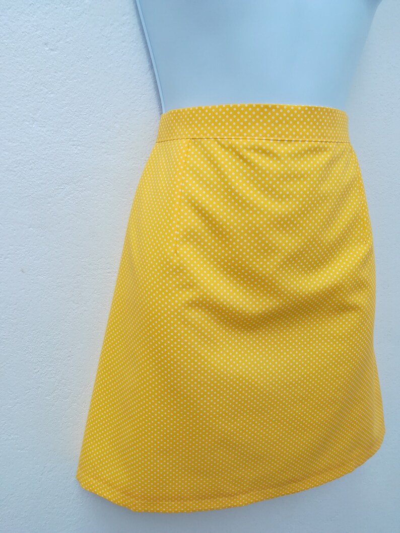 May include: A yellow skirt with white polka dots. The skirt is knee-length and has a straight silhouette.