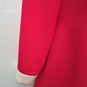 May include: A red dress with a white collar and cuffs. The dress is made of a smooth fabric.