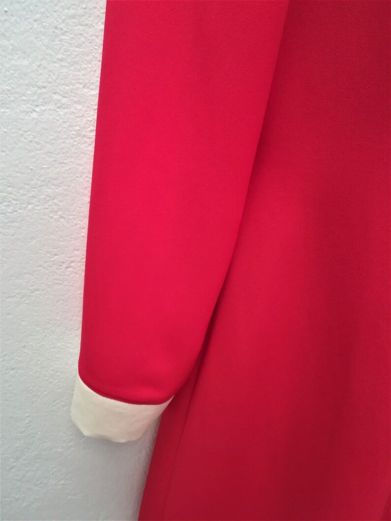 May include: A red dress with a white collar and cuffs. The dress is made of a smooth fabric.