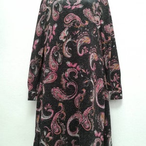 May include: A black long-sleeved dress with a paisley print in shades of pink, white, and orange. The dress has a collared neckline and a button closure.