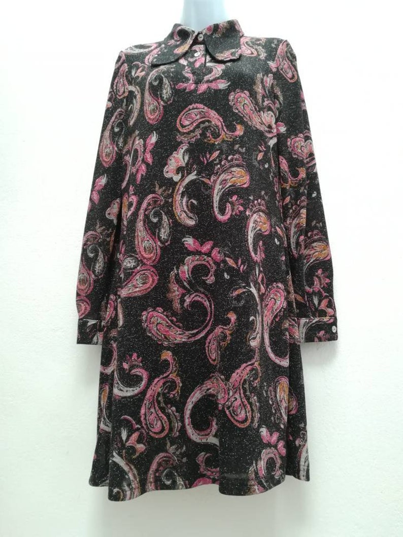 May include: A black long-sleeved dress with a paisley print in shades of pink, white, and orange. The dress has a collared neckline and a button closure.