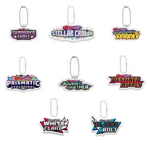 Può includere: Una collezione di sette portachiavi della serie "Scarlet & Violet". Ogni portachiavi presenta un design unico con testi come "Shrouded Fable", "Stellar Crowd", "Surging Sparks", "Prismatic Evolutions", "Journey Together", "Destined Rivals", "White Flare" e "Black Bolt".