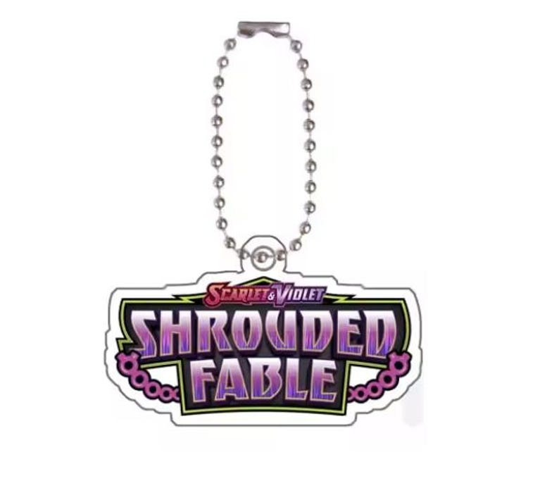 Pu&ograve; includere: Un portachiavi con la scritta "Scarlet & Violet Shrouded Fable" in viola e bianco. Ha una catena argentata e una chiusura in metallo.