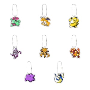 Può includere: Una collezione di otto portachiavi con personaggi in pixel art, ognuno caratterizzato da un design unico di creatura dai colori vivaci e una catenella a palline argentata. Il set include figure come una pianta verde, un'anatra gialla e un blob viola.