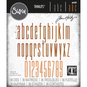 May include: Sizzix Thinlits Tim Holtz alphabet and number metal cutting dies set. The package displays the full lowercase alphabet and numbers 0-9 in a tall, thin orange font. A 2-inch measurement indicator is visible next to the letter a.