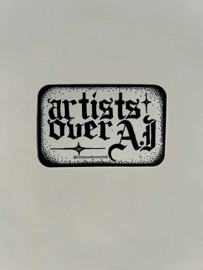 以下が含まれることがあります： 長方形のステッカー。角が丸く、ゴシック体の「artists over Aj」の文字が描かれています。ステッカーは白黒で、点線で縁取られ、Instagramのハンドルネーム@crimsonhoneyinkも表示されています。