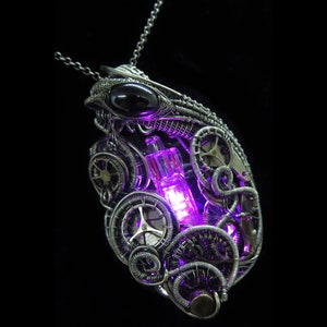 May include: A silver necklace with a pendant featuring a glowing purple light bulb surrounded by intricate gears and wirework. The pendant also has a black gemstone.