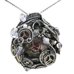 May include: A silver-toned steampunk pendant necklace. The pendant features a complex arrangement of gears, wires, and clear crystal accents. The necklace has a delicate chain and a unique, industrial design.