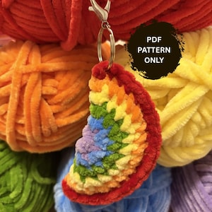 May include: A crochet keychain shaped like a rainbow slice, featuring concentric arcs of red, orange, yellow, green, blue, and purple yarn. The keychain is attached to a silver metal lobster clasp and ring. A black circular graphic reads PDF PATTERN ONLY.