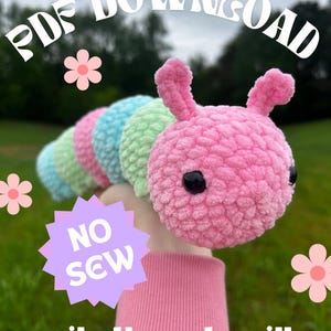 May include: A handmade, plush caterpillar toy in shades of pink, blue, and green. The caterpillar has black eyes and a smiling expression. The image includes the text "PDF DOWNLOAD", "NO SEW", and "camila the caterpillar".
