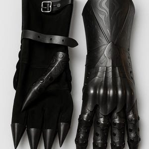 May include: A pair of black gauntlets featuring articulated finger plates with pointed tips, embossed scrollwork patterns on the hand and wrist sections, and adjustable leather straps with metal buckles at the forearm for a secure fit.