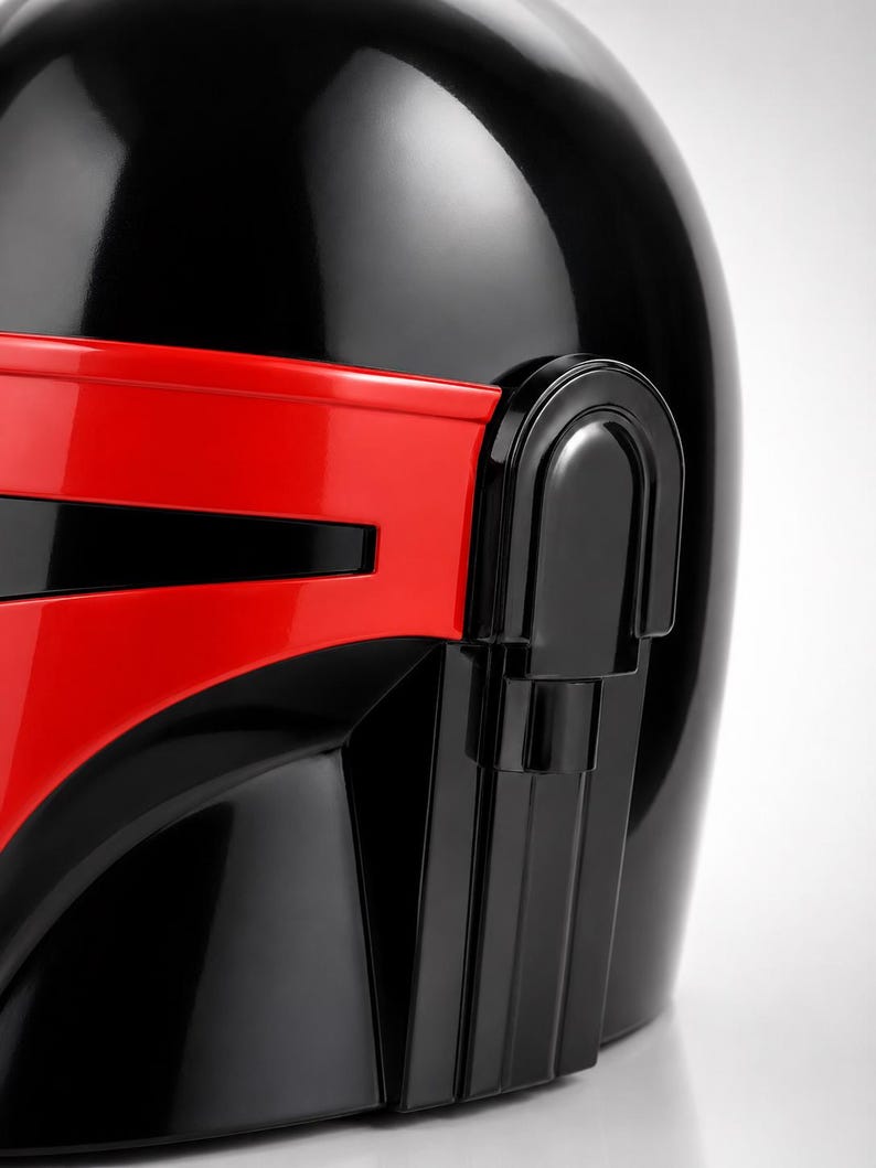 May include: A glossy black helmet featuring a prominent, horizontal red visor section across the front. The helmet has a smooth, rounded dome and a distinct vertical side panel detail integrated into the design, creating a bold contrast.