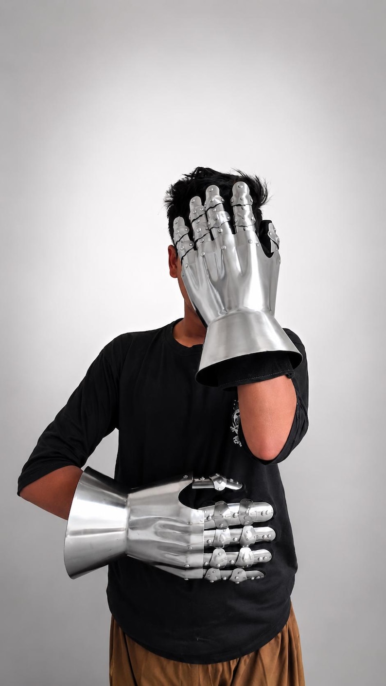 May include: A pair of polished steel gauntlets featuring articulated finger plates, riveted construction, and flared cuffs. These metallic hand protectors are designed with segmented sections for the fingers and thumb, providing a reflective surface.