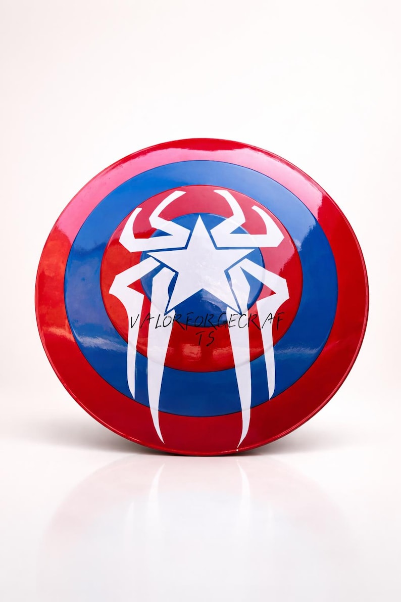 May include: A round shield with a red, white, and blue color scheme. The shield has a white star in the center, with white stylized wing-like shapes. The text "VALOR FORGE CRAFTS" is visible on the shield.