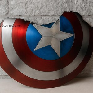 May include: A distressed shield with a red, white, and blue color scheme. The shield features a central blue circle with a white star, surrounded by red and silver stripes. The shield has a battle-worn appearance.