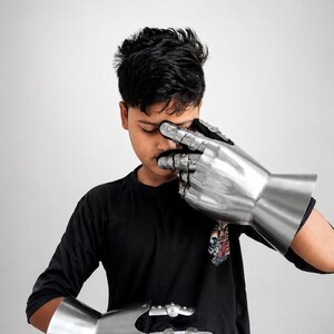 May include: A pair of articulated metal gauntlets featuring a polished silver finish, segmented finger plates, and a flared cuff design. These protective hand coverings are constructed with multiple overlapping steel plates that allow for finger movement.