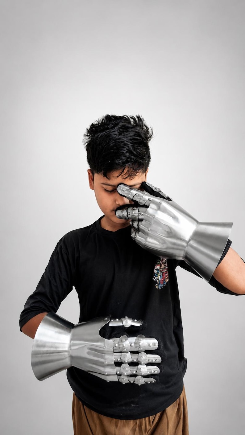 May include: A pair of articulated metal gauntlets featuring a polished silver finish, segmented finger plates, and a flared cuff design. These protective hand coverings are constructed with multiple overlapping steel plates that allow for finger movement.