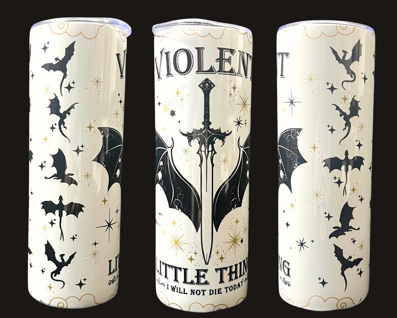 Op de afbeelding: Een witte beker met een zwart en goud design. Het ontwerp bevat vleermuizen, sterren en de tekst "VIOLENT LITTLE THING I WILL NOT DIE TODAY" met een zwaard en vleermuisvleugels. De beker heeft een zilveren deksel.