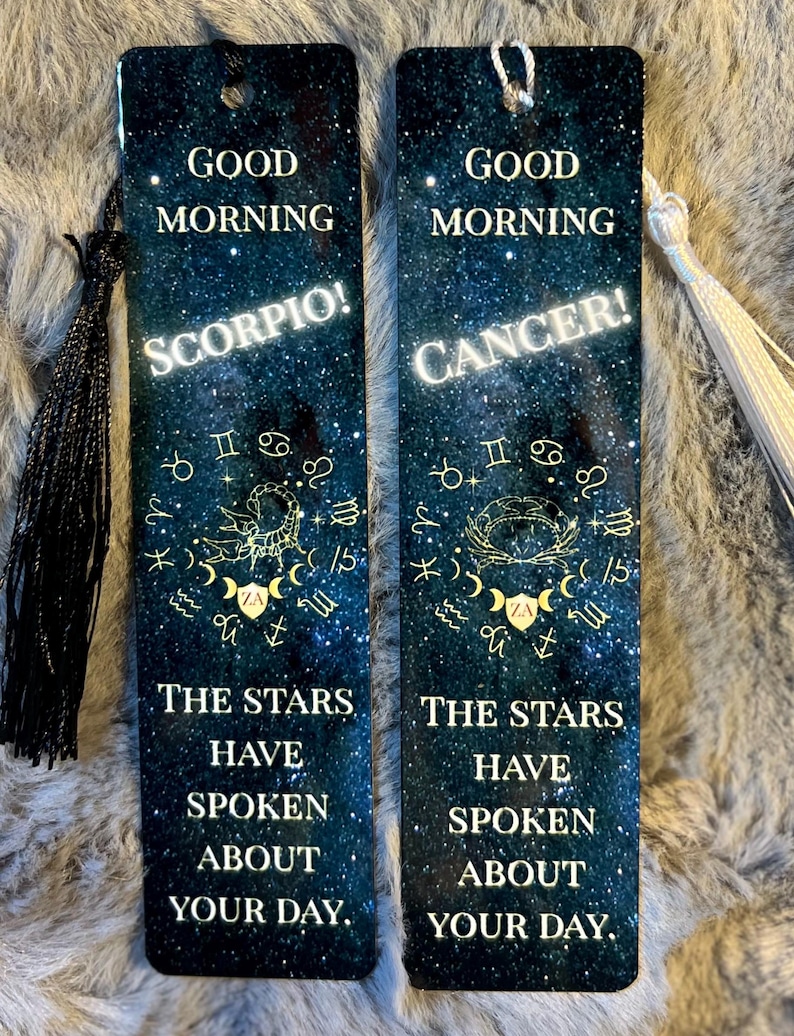 May include: Two rectangular bookmarks with a starry night sky design. One bookmark says "Good Morning Scorpio!" and the other says "Good Morning Cancer!". Both bookmarks have the text "The stars have spoken about your day."