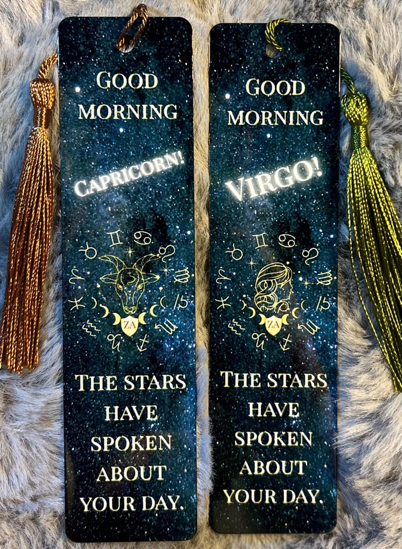 May include: Two rectangular bookmarks with a starry night sky design. One features "Capricorn!" and the other "Virgo!" with zodiac symbols. Text reads "Good Morning" and "The Stars Have Spoken About Your Day." Each has a tassel.