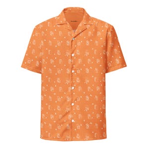 May include: Orange short-sleeved button-down shirt with a camp collar. The shirt features a repeating white pattern of stylized buildings and small white dots. The shirt has a classic fit and is made of a lightweight fabric.