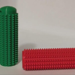 May include: Two cylindrical massage tools. One is upright and green, the other is horizontal and red. Both have a textured surface with evenly spaced, cone-shaped protrusions. The green cylinder has a small hole at the top.