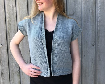 May include: A light blue knitted cardigan with short sleeves and a V-neck. The cardigan is open in the front and has a ribbed trim.