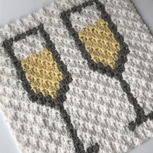 Puede incluir: Un paño de cocina de crochet blanco con dos copas de vino de crochet grises y amarillas.