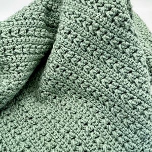 May include: A soft, green crocheted blanket with a textured, diamond-shaped pattern.