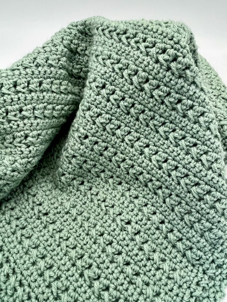 May include: A soft, green crocheted blanket with a textured, diamond-shaped pattern.