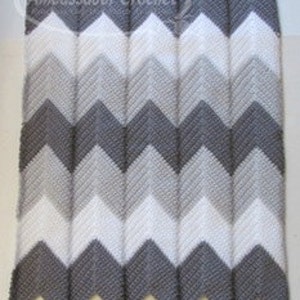 Op de afbeelding: Een grijze, witte en lichtgrijze chevron-gepatroneerde gehaakte babydeken.