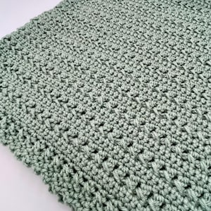 May include: A soft, sage green crocheted blanket with a textured stitch pattern.