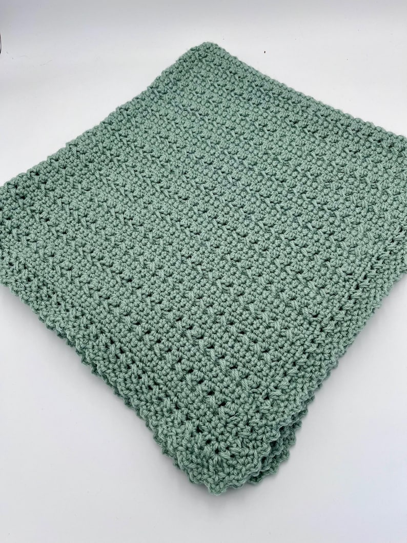 May include: A soft, sage green crocheted blanket with a textured stitch pattern.