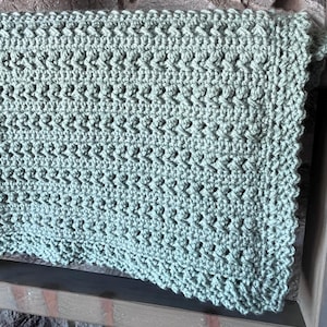 May include: A soft, sage green crocheted blanket with a textured stitch pattern.