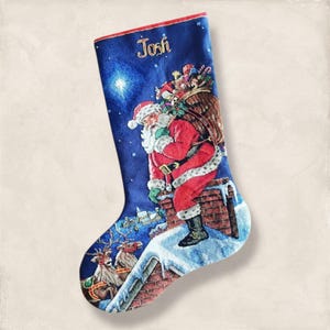 May include: A blue Christmas stocking featuring Santa Claus on a rooftop, with reindeer and a sleigh in the background. The stocking has the name "Josh" embroidered in gold. The trim is red.