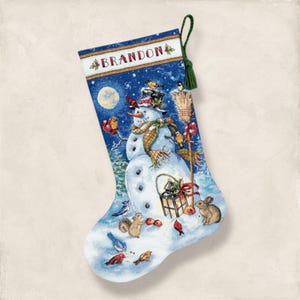 May include: A blue Christmas stocking featuring a snowman with a hat, scarf, and carrot nose, surrounded by birds and a rabbit. The word "BRANDON" is printed at the top. A green tassel hangs from the top.