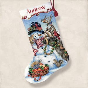 May include: A Christmas stocking with a snowman, reindeer, and squirrel design. The stocking has a red tassel and the name "Andrew" printed at the top. The snowman wears a hat and scarf, and the reindeer has a green garland.