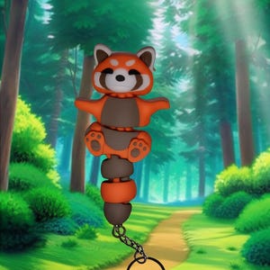Peut inclure: Un porte-clés représentant un panda roux avec un anneau noir. Le panda roux est orange et marron avec un visage blanc. Le porte-clés est composé de plusieurs pièces reliées. L'arrière-plan est une scène de forêt.