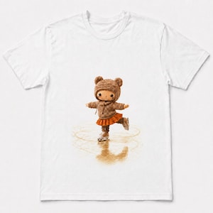 May include: A white t-shirt featuring a graphic of a small doll wearing a brown knit bear-ear hat, a brown sweater, and an orange skirt. The doll is depicted ice skating on a reflective surface, creating circular marks on the ice below its skates.
