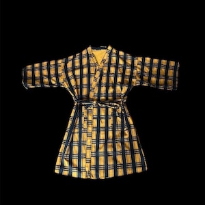 May include: A yellow and black plaid robe with a long sleeve and a tie belt.