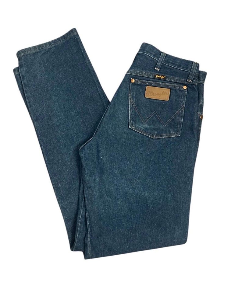 Op de afbeelding: Donkerblauwe Wrangler jeans van denim. De jeans hebben een klassiek ontwerp met vijf zakken, een bruine leren patch met het Wrangler-logo en een rechte pijp. De jeans hebben een medium wassing en lijken in goede staat te verkeren.