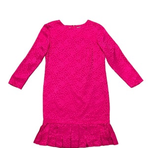 May include: A pink dress with a small white polka dot pattern. The dress has long sleeves and a ruffled hem.