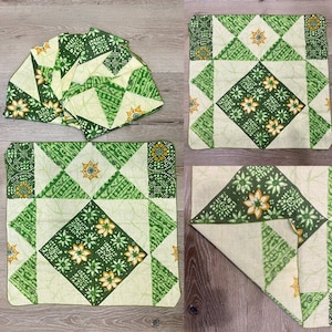 以下が含まれることがあります： 緑と白の布製のランチョンマットのセットで、正方形と三角形の幾何学模様が施されています。模様には緑と黄色の花と、各正方形の中央に黄色の星が描かれています。