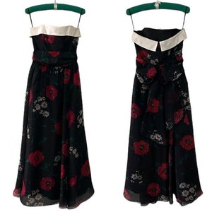 May include: A black strapless maxi dress with a white collar and a red floral print. The dress has a sash that ties in a bow at the back.